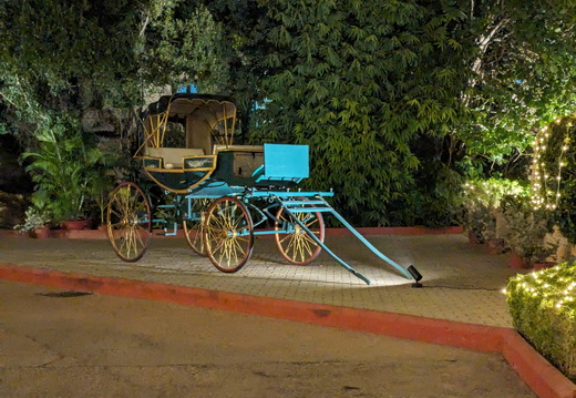 A vintage horse-drawn carriage sits on a driveway at night