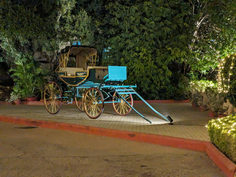 A vintage horse-drawn carriage sits on a driveway at night