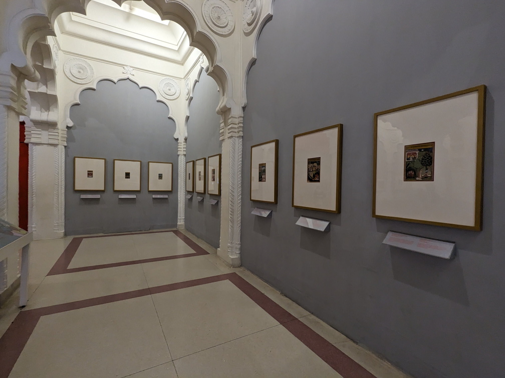 A long, arched hallway with paintings on the walls