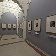 A long, arched hallway with paintings on the walls